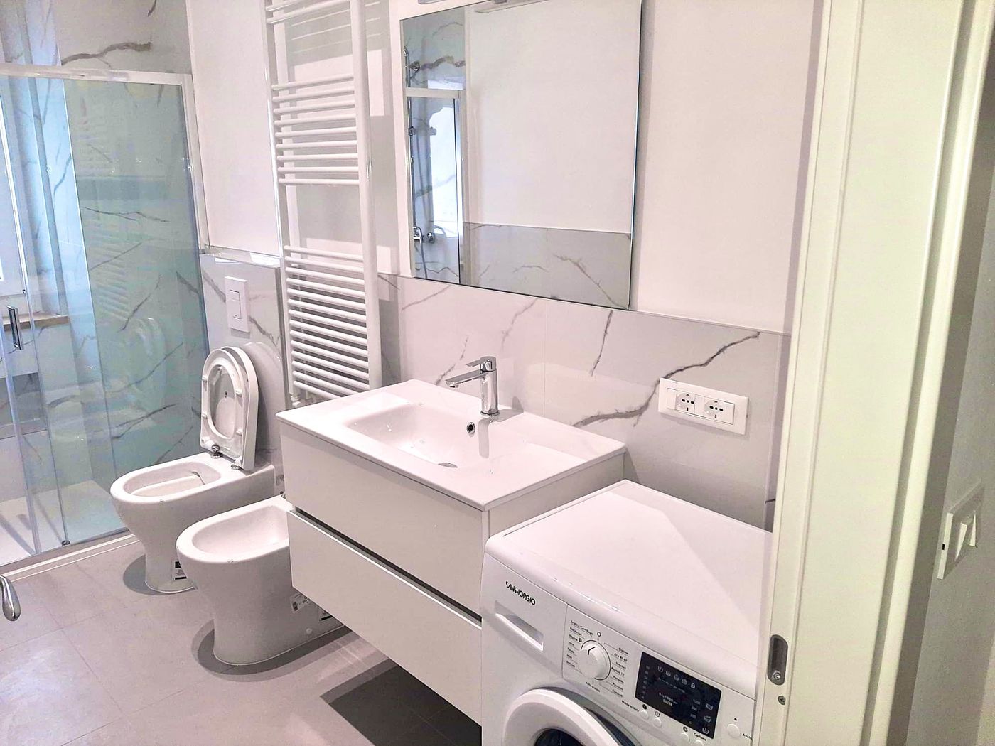 Bagno ristrutturato con box doccia, sanitari sospesi e lavatrice integrata